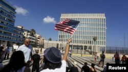 Una mujer ondea una bandera estadounidense frente a la Embajada de EE.UU. en La Habana, Cuba, el lunes, 20 de julio de 2015.