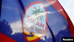 FILE - Local residents display a Guam flag during a peace rally at Chief Quipuha Park, on the island of Guam, a U.S. Pacific Territory, Aug. 14, 2017. Guam wants to decide its future with a nonbinding vote.
