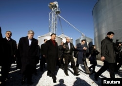 FILE - Chinese Vice President Xi Jinping, third from left, talks with Rick Kimberley, center, and Iowa Governor Terry Branstad, second from left, during a tour of Kimberley's farm, in Maxwell, Iowa, Feb. 16, 2012.