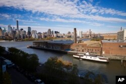 In this Wednesday, Nov. 7, 2018, photo, a rusting ferryboat is docked next to an aging industrial warehouse on Long Island City's Anable Basin in the Queens borough of New York. Across the East River is midtown Manhattan, top left.