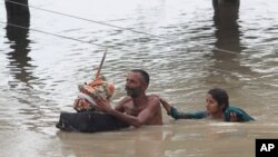 Dân làng lội qua nước lụt ở Rajanpur, Pakistan, hôm 23/7.