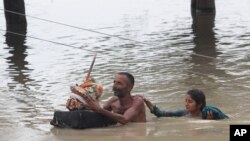 Pakistan villagers wade through floodwaters in Rajanpur, Pakistan, Thursday, July 23, 2015. 