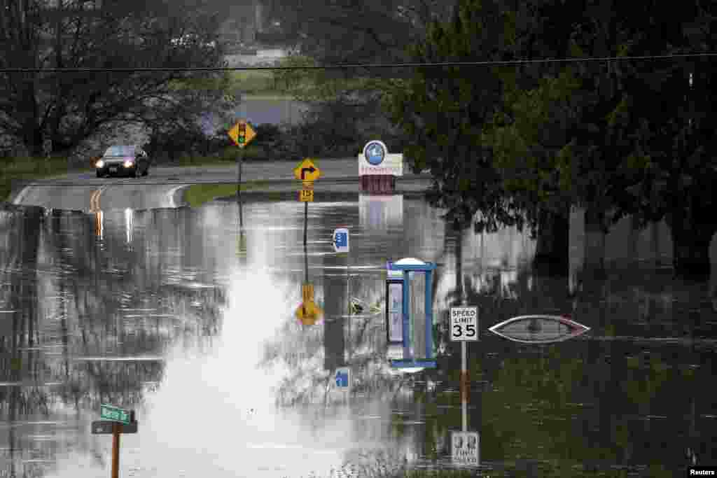 Sebuah mobil mendekati jalanan yang digenangi air dari Sungai Stillaguamish, di Stanwood, Washington, USA, 18 November 2015. Sedikitnya tiga orang tewas dan listrik padam di sekitar 250.000 rumah dan gedung bisnis di negara bagian Washington setelah badai merubuhkan pohon-pohon dan menyebabkan longsor menurut pemerintah.