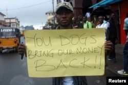 A Liberian demonstrator holds a sign during a protest in Monrovia, Liberia, Sept. 24, 2018.