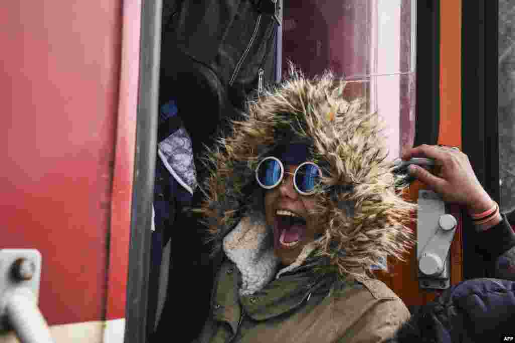 زنی که عینک آفتابی زده، خوشحال، سوار قطار مهاجران و پناهجویان شده است؛ مرز یونان و مقدونیه. &nbsp;