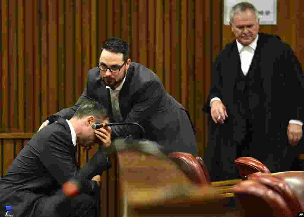 A crying Oscar Pistorius is comforted by his brother as his defense lawyer, Barry Roux, looks on during the third day of sentencing hearings in the high court in Pretoria, South Africa, Oct. 15, 2014. 