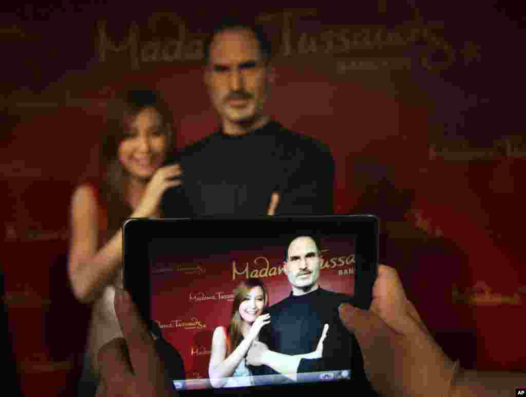 Seorang pengunjung Thailand berpose dengan patung lilin pendiri perusahaan Apple Steve Jobs yang baru diluncurkan, di museum lilin Madame Tussauds, Bangkok, Thailand.