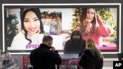 Cashier Druhan Parker, center, works behind a plexiglass shield Nov. 19, 2020, as he checks out shoppers at an Ulta beauty store on Chicago's Magnificent Mile as the pandemic has forced people to spend more time with themselves than ever.