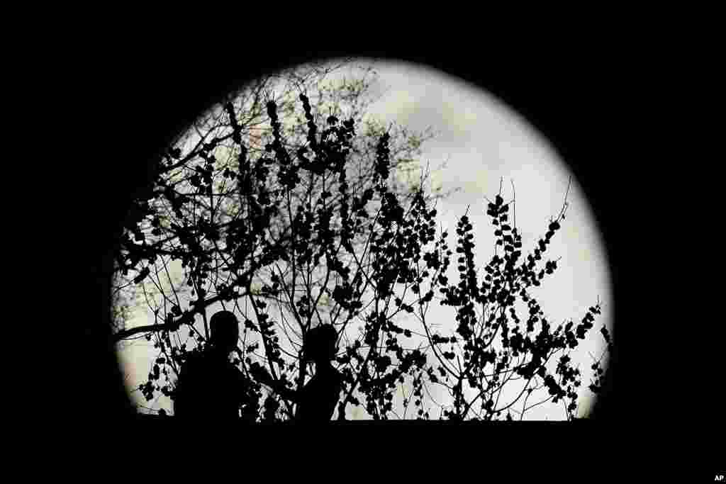 A couple are silhouetted against the rising full moon as they gather in a park, March 28, 2021, in Kansas City, Missouri.