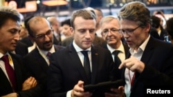 French President Emmanuel Macron (C) holds a device at the Viva Technology event dedicated to start-ups development, innovation and digital technology in Paris, June 15, 2017. 