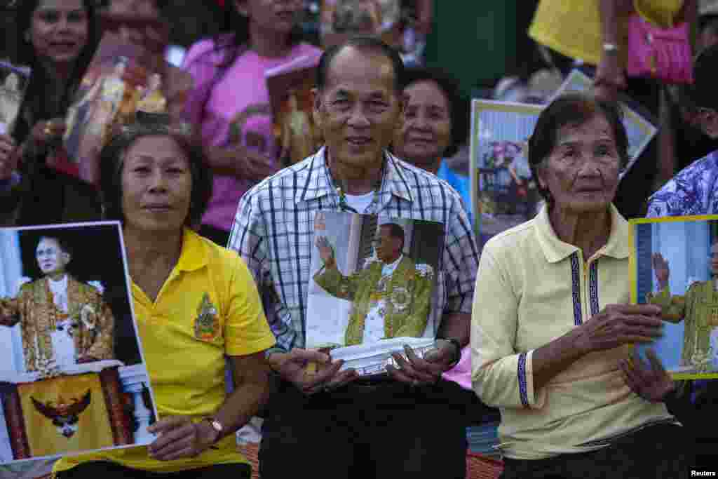 Well-wishers hold pictures of Thailand&#39;s King Bhumibol Adulyadej, Dec. 4, 2013,&nbsp;as they camp outside the palace where he is staying in Hua Hin, Prachuap Khiri Khan province, Thailand, a day before his birthday.