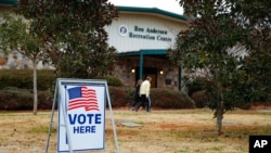 FILE - Voters return to their vehicles after early voting for the Senate runoff election, at Ron Anderson Recreation Center, Dec. 17, 2020, in Powder Springs, Ga. 