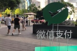 FILE - People walk past a WeChat Pay sign at the Tencent company headquarters, in Shenzhen, Guangdong province, China, Aug. 7, 2020.