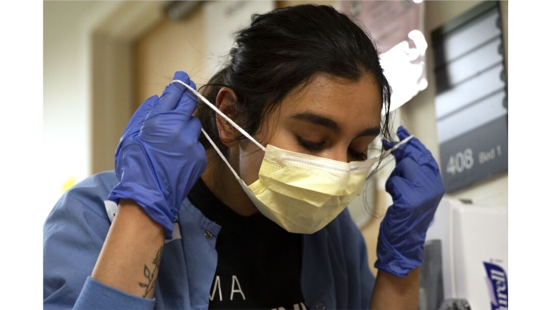 Nurse Liliana Palacios removes her mask and PPE after tending to a patient with COVID-19 in the acute care COVID unit at Harborview Medical Center in Seattle, Wash., on May 7, 2020.