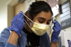 Nurse Liliana Palacios removes her mask and PPE after tending to a patient with COVID-19 in the acute care COVID unit at Harborview Medical Center in Seattle, Wash., on May 7, 2020.