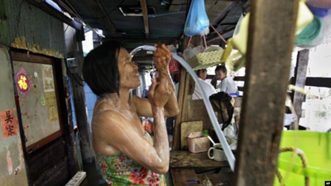 A Thai woman takes a shower in a narrow alley in a flooded neighborhood in Bangkok, Thailand, November 8, 2011.