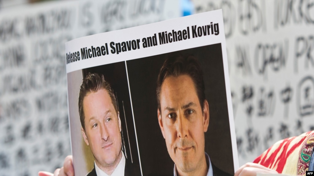 (资料照) 加拿大抗议人士举着加拿大商人迈克尔·斯帕弗（Michael Spavor）和加拿大前外交官康明凯（Michael Kovrig）的头像的标语，抗议中国政府任意拘押这两位加拿大公民。（美联社）