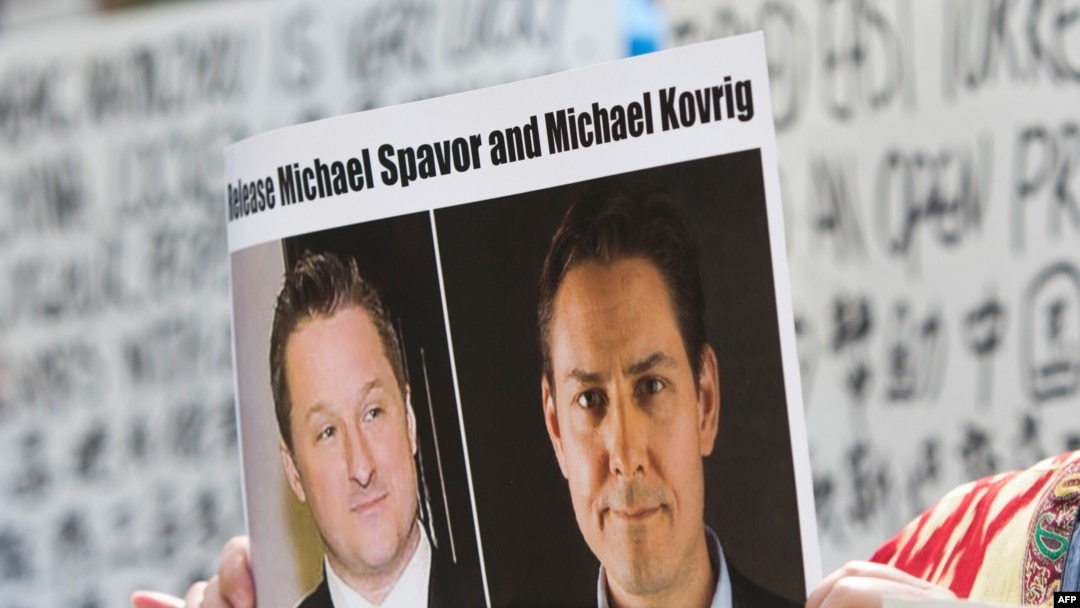  加拿大抗議人士舉著加拿大商人邁克爾·斯帕弗（Michael Spavor）和加拿大前外交官康明凱（Michael Kovrig）的頭像的標語，抗議中國政府任意拘押這兩位加拿大公民。（美聯社）
