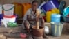 FILE - A girl displaced as a result of Boko Haram attacks in the northeast region of Nigeria, uses a mortar and pestle at a camp for internally displaced people in Yola, Adamawa State, Jan. 14, 2015.