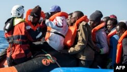 Un groupe de 47 migrants est assisté par un membre de l'équipage de Sea-Watch 3, à gauche, lors de leur transfert d'un bateau pneumatique secouru à bord d'un Sea-Watch 3 RHIB 