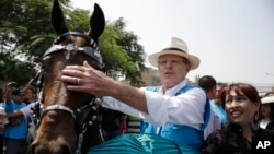 Presidential candidate Pedro Pablo Kuczynski of the Peruvians for Change party pats a horse during a rally on the outskirts of Lima, Peru, May 3, 2016.