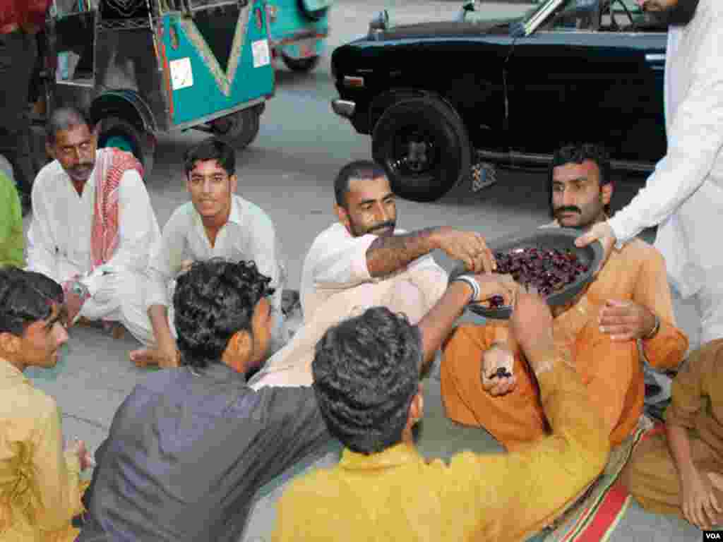 سڑک پر روزہ افطار کرنے کے لیے آنے والے افراد میں کھجور تقسیم کی جا رہی ہے