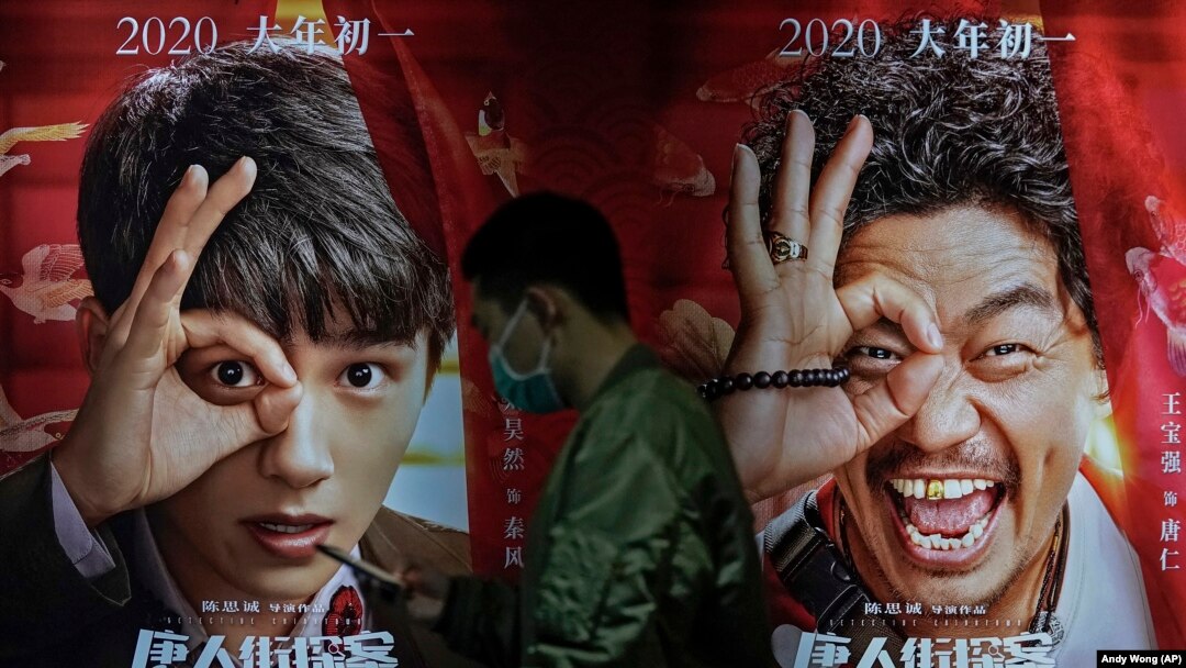 Seorang pria mengenakan masker untuk mengurangi penyebaran virus corona melintas di depan poster film di Poly Cinema, di Beijing, China, 25 Februari 2021. (Foto: Andy Wong/Associated Press)