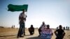 A protester holds a placard as another holds an Islamic movement flag during a demonstration to show their solidarity with Bedouin citizens, near the Bedouin townof Rahat in southern Israel August 1, 2013.