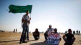 A protester holds a placard as another holds an Islamic movement flag during a demonstration to show their solidarity with Bedouin citizens, near the Bedouin townof Rahat in southern Israel August 1, 2013.