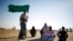 A protester holds a placard as another holds an Islamic movement flag during a demonstration to show their solidarity with Bedouin citizens, near the Bedouin townof Rahat in southern Israel August 1, 2013.