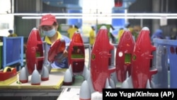 In this May 27, 2020, photo released by Xinhua News Agency, a worker makes plastic toys at a factory in Zhangjiajie, central China's Hunan Province.