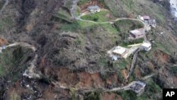 This photo made available by the U.S. Coast Guard, shows homes near a washed out road in Utuado, Puerto Rico, Oct. 3, 2017. 