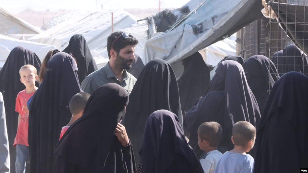 Para perempuan yang ditahan di kamp al-Hol mengerubungi seorang jurnalis sambil mengeluhkan anak-anak mereka yang dibawa ke pusat deradikalisasi, di Suriah, pada 20 Oktober 2021. (Foto: VOA/Ali Zeyno)