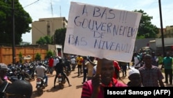FILE: A members of Burkinabe workers' unions and civil society associations holds a placard reading "Enough of this bad standard of government" during a march called by the UAS union to call for better security measures against terrorism, in Ouagadougou on September 16, 2019