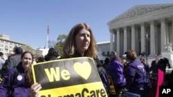 Holding a sign saying 'We Love ObamaCare' supporters of health care reform rally in front of the Supreme Court in Washington, March 27, 2012. 