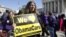 Holding a sign saying 'We Love ObamaCare' supporters of health care reform rally in front of the Supreme Court in Washington, March 27, 2012. 