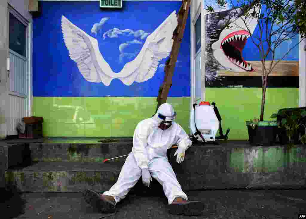 A health worker rests after disinfecting a public restroom at a bus station in Bandung, West Java, Indonesia.