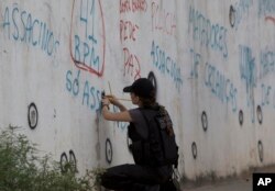 A police officer checks the bullet holes in the wall of the school where Maria Eduarda Conceicao was killed by a stray bullet during a shootout between police and alleged drug traffickers in the Acari neighborhood, in Rio de Janeiro, Brazil, April 12, 2017.