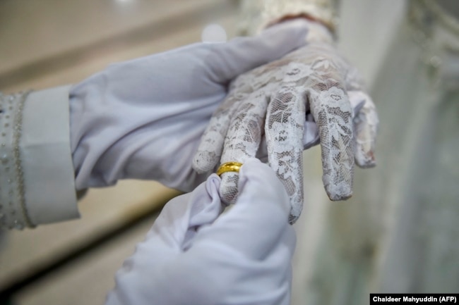 Seorang pengantin pria memasang cincin di jari istrinya saat upacara pernikahan di sebuah masjid di Banda Aceh pada 3 Juni 2020. (Foto: AFP/Chaideer Mahyuddin)