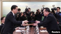 تبادل سند میان ری سون کیوون سرپرست هیات کره شمالی و پیو میونگ گیون همتای او از کره جنوبی در محل مذاکرات در منطقه حائل بین دو کره