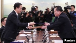 Head of the North Korean delegation, Ri Son Gwon exchanges documents with South Korean counterpart Cho Myoung-gyon after their meeting at the truce village of Panmunjom in the demilitarised zone separating the two Koreas, South Korea, January 9, 2018.