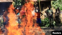 Un M23 rebelle et les habitants du lieu regardent bruler des sacs de fétiches dans le village de Kako, dans le Nord-Kivum RDC, 15 mai 2013. 