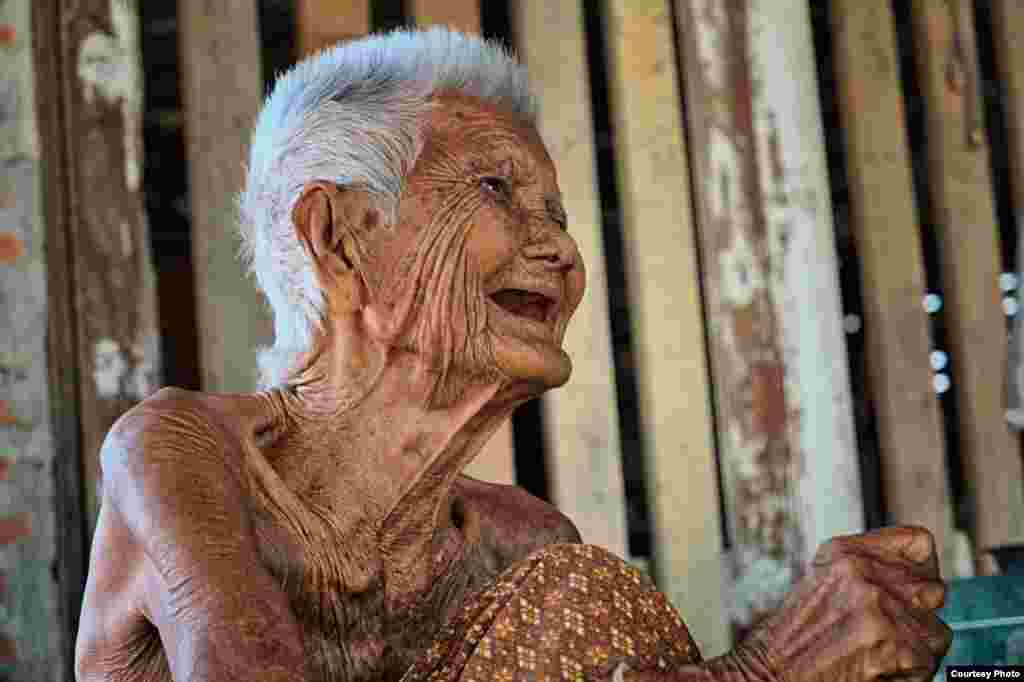 A Thai woman laughs as she is asked how old she is. At 105-years-old, she is still able to make others around her smile as she sits in the shade on a bamboo bed in the village of Satuek, Buriram province, northeast Thailand. (Photo taken on Sept. 27, 2014, by Matthew Richards/VOA reader/Thailand) 