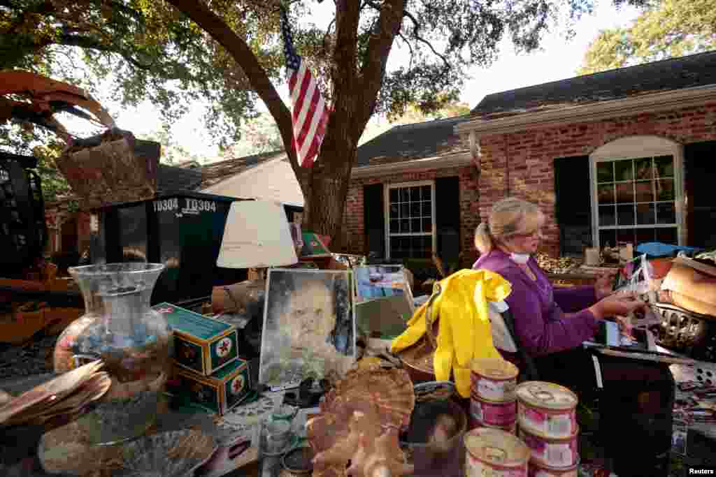 Seorang ibu berusaha menyelamatkan foto-foto keluarganya setelah rumahnya dilanda banjir akibat badai Harvey di Houston, Texas.