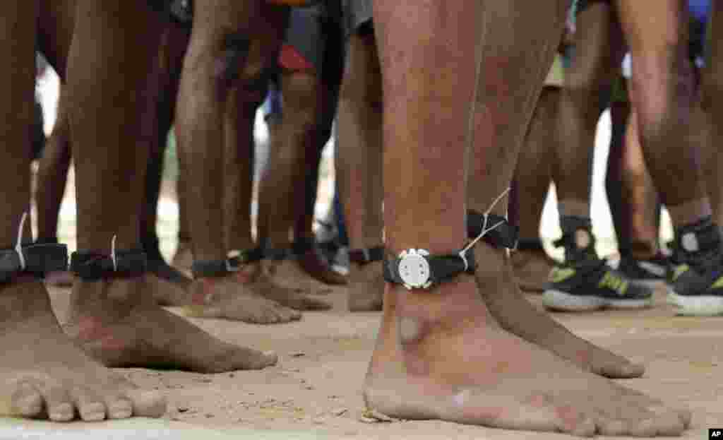 Candidates, many barefoot and unable to afford running shoes, are seen tagged with chips used to record their distance, wait for their turn to run during a recruitment drive for Uttar Pradesh state police, in Allahabad, India.