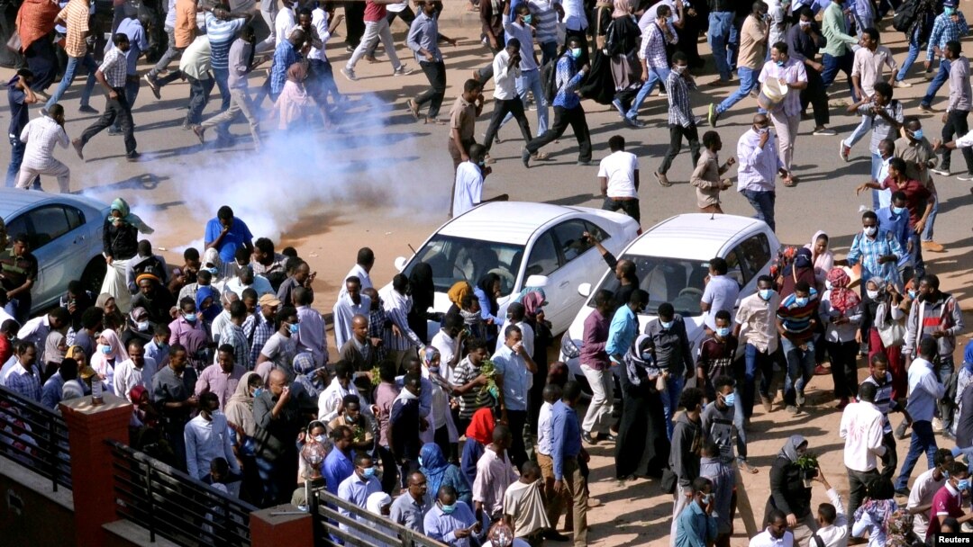 FILE - Sudanese demonstrators run from tear gas lobbed to disperse them as they march along the street during anti-government protests in Khartoum, Sudan, Dec. 25, 2018.