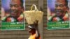 FILE - A street vendor carries fruit while passing campaign posters of President Emmerson Mnangagwa's ruling ZANU-PF party, in Mutare, Zimbabwe, May 19, 2018. 
