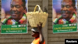 FILE - A street vendor carries fruit while passing campaign posters of President Emmerson Mnangagwa's ruling ZANU-PF party, in Mutare, Zimbabwe, May 19, 2018. 