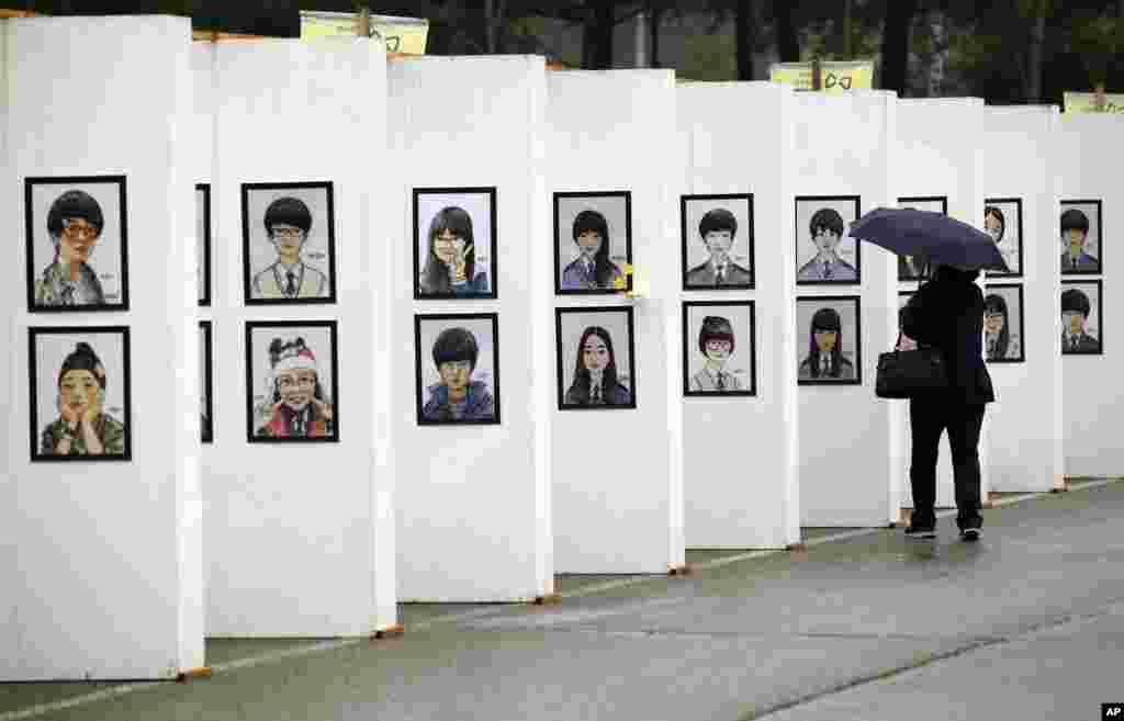 Seorang perempuan melihat karikatur para korban kapal feri Sewol yang tenggelam, di altar memorial di Ansan, Korea Selatan (16/4). (AP/Lee Jin-man)