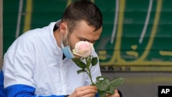 Un hombre con una máscara que cubre parcialmente su rostro sostiene una rosa en Bucarest, Rumania, el jueves 8 de octubre de 2020. 